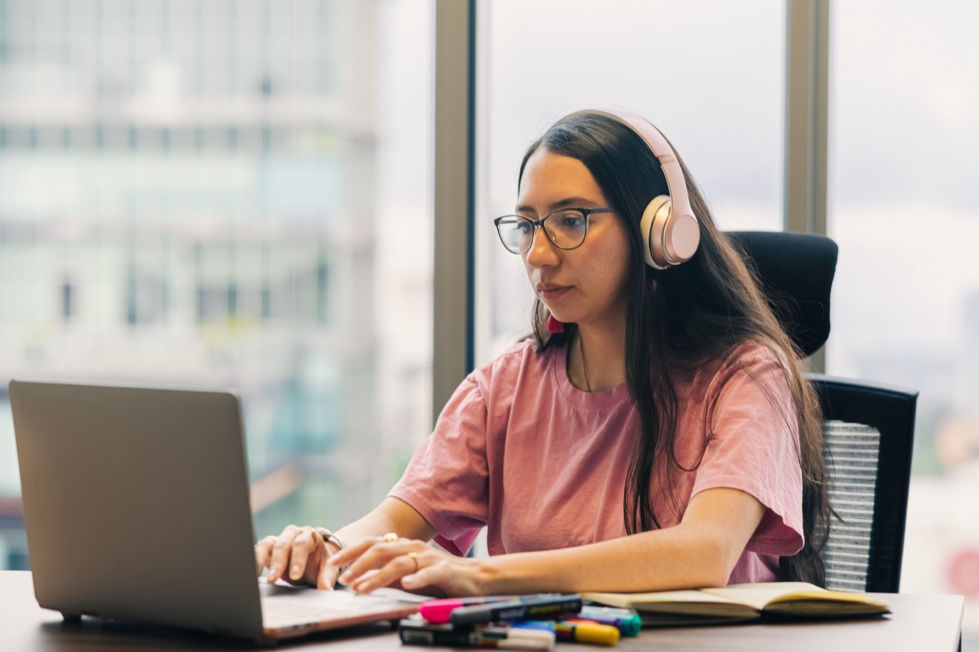 A person with headphones and glasses following an online class at home