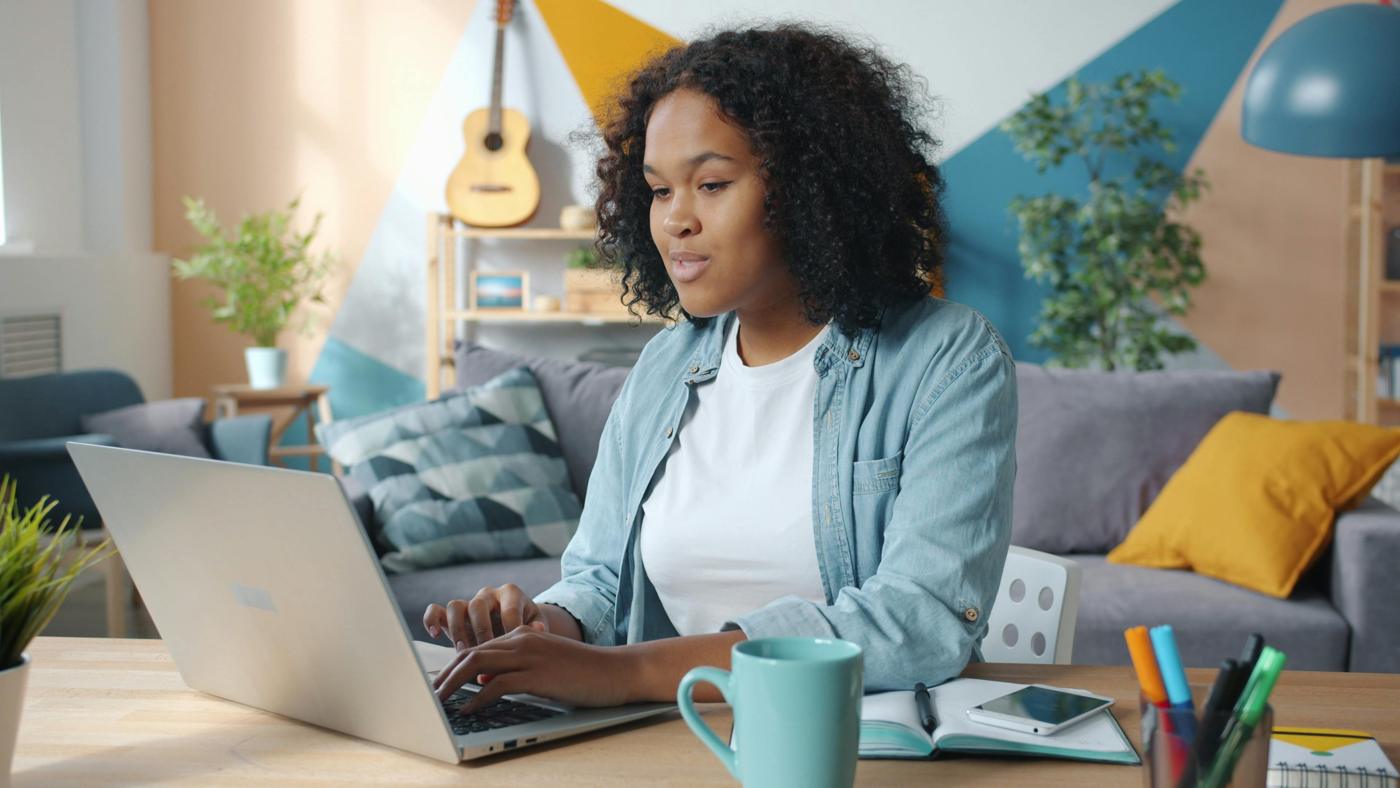 A person smiling at a laptop at home