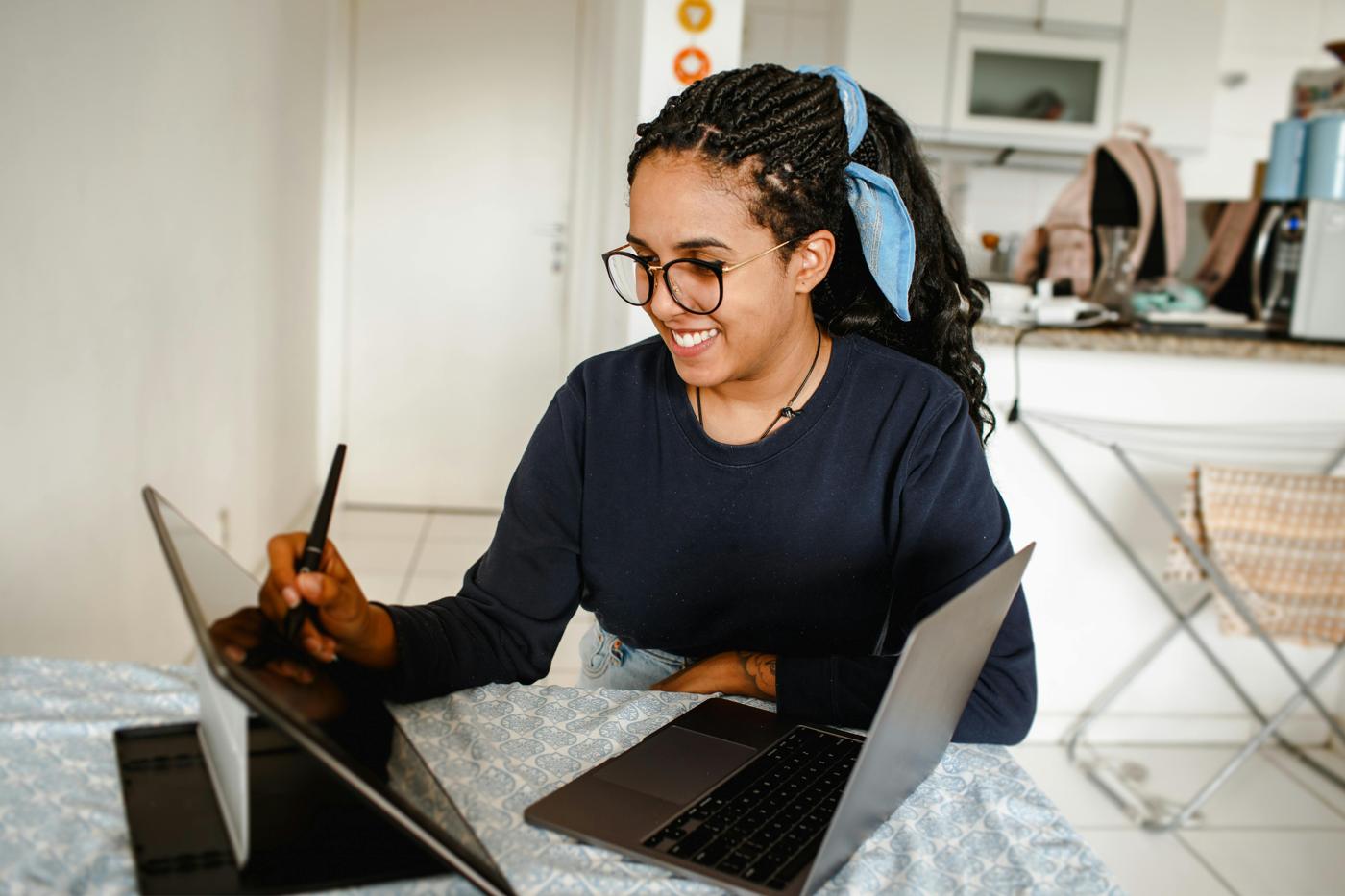 A person with glasses working with a laptop and tablet at home